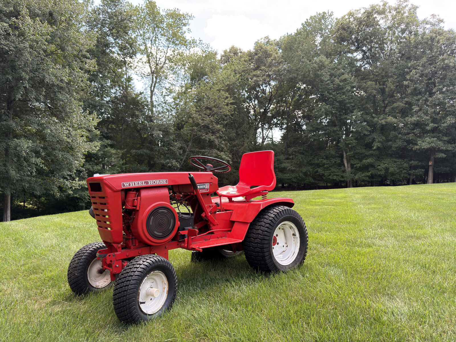 Red Wheel Horse tractor parked on a green lawn.